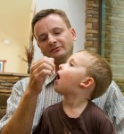 A man gives his son allergy drops, which can be customized to address multiple allergies at once.